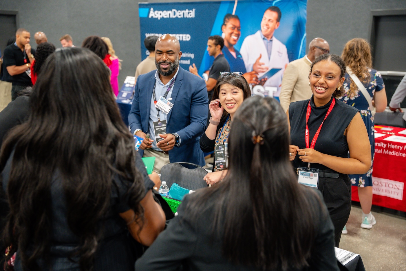 Attendees talking in groups on the exhibit floor, convention badges around their necks